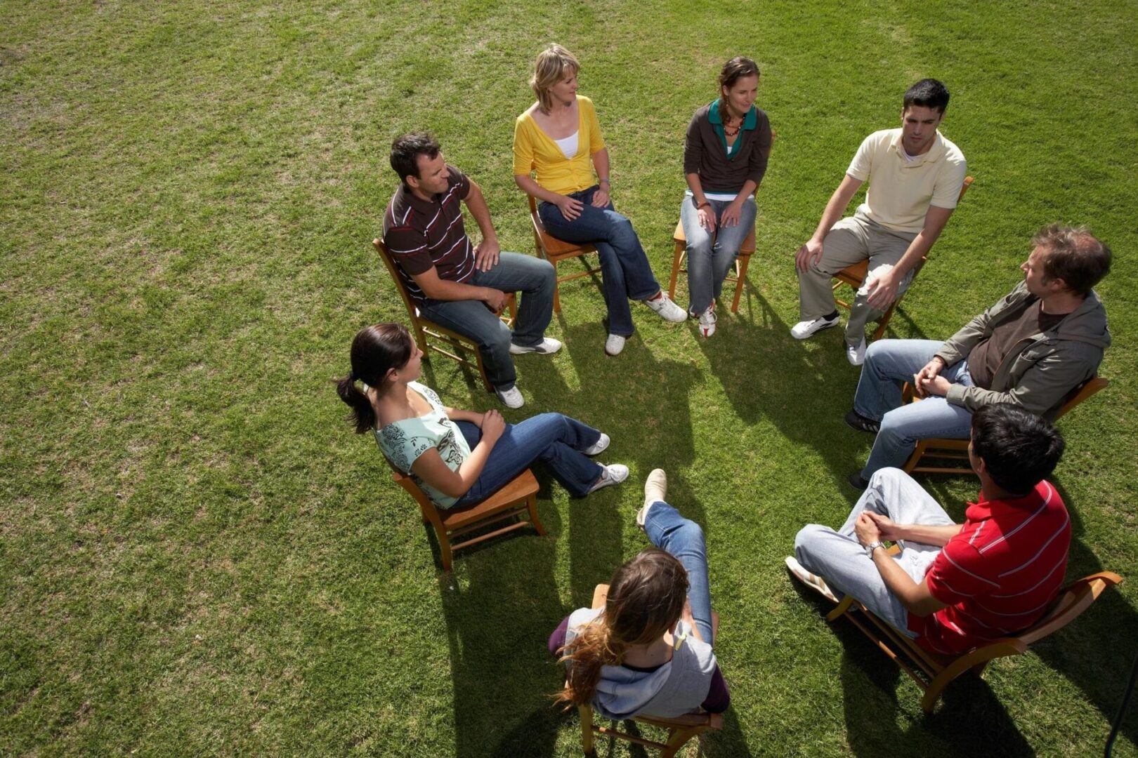 A group of people sitting in chairs on the grass.