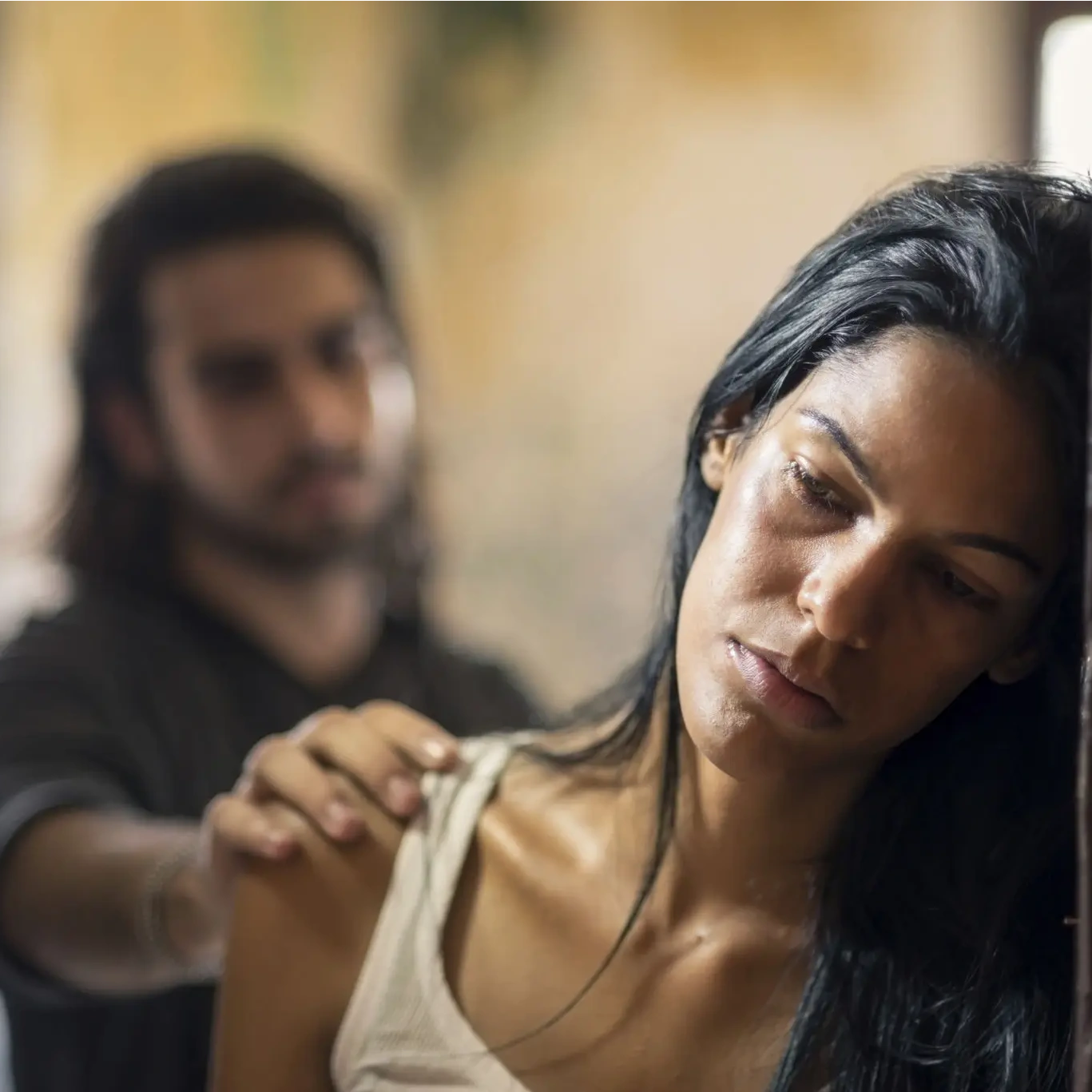 Close-up of thoughtful woman, man in distance.