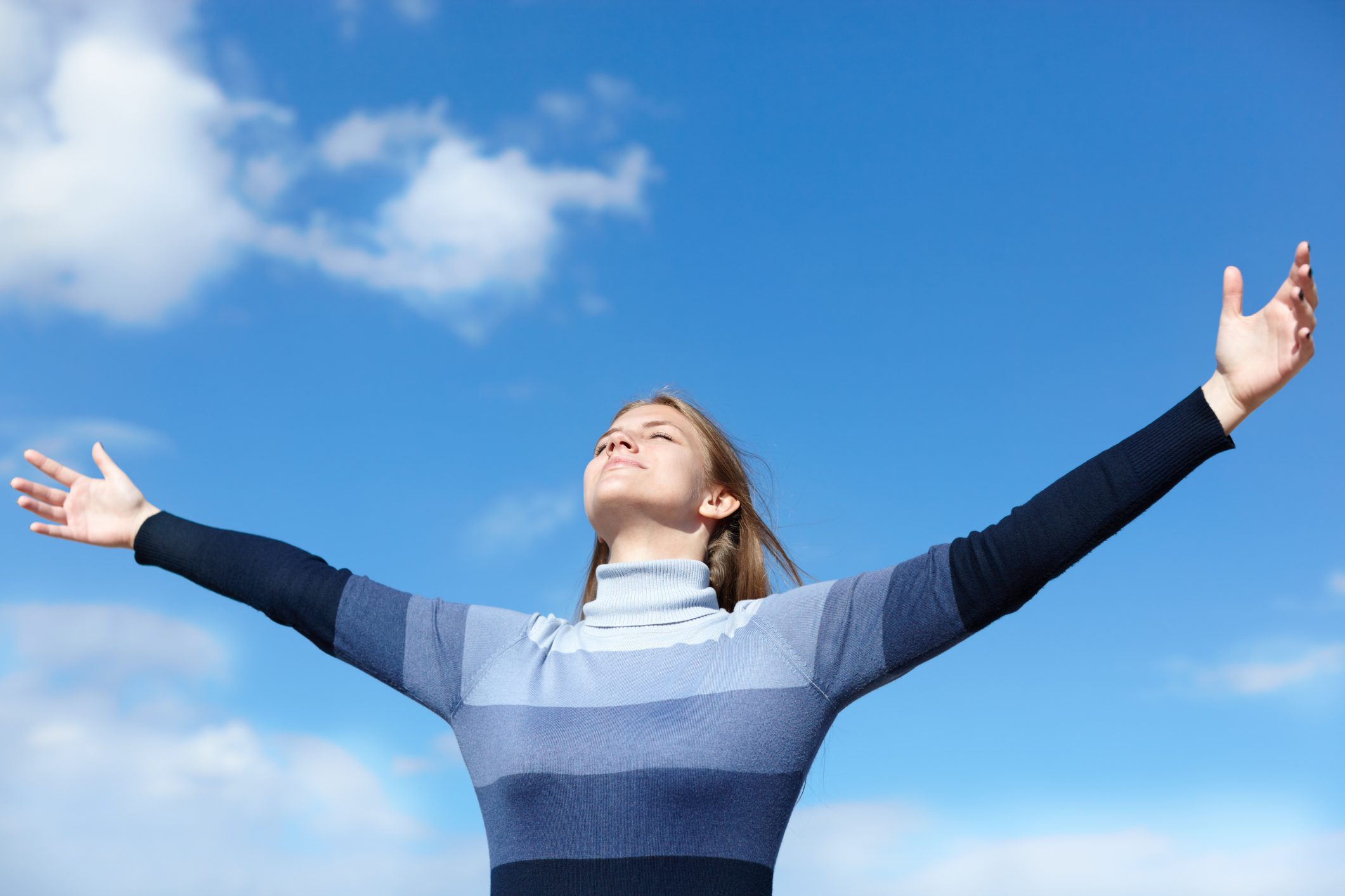 happy young woman on blue sky background, natural sunlight, selective focus